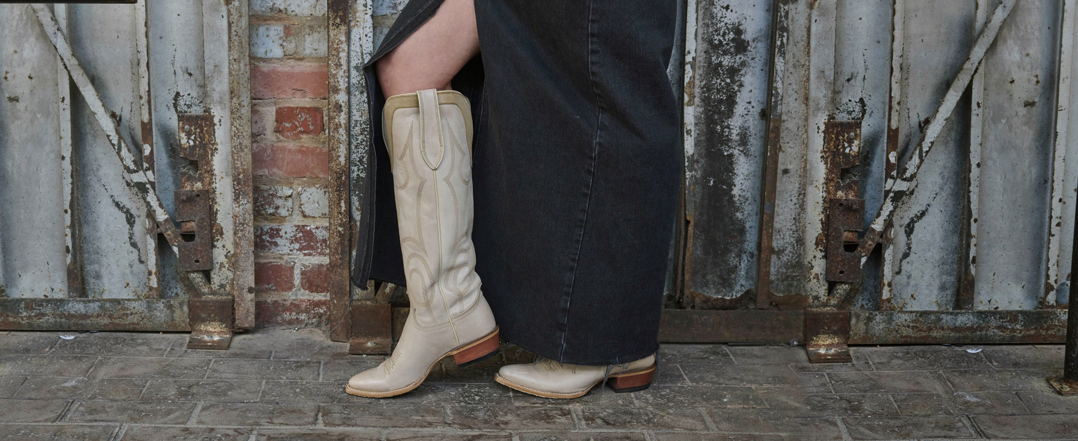 Woman wearing Verlie 17” Western boots in cream with a long skirt. 